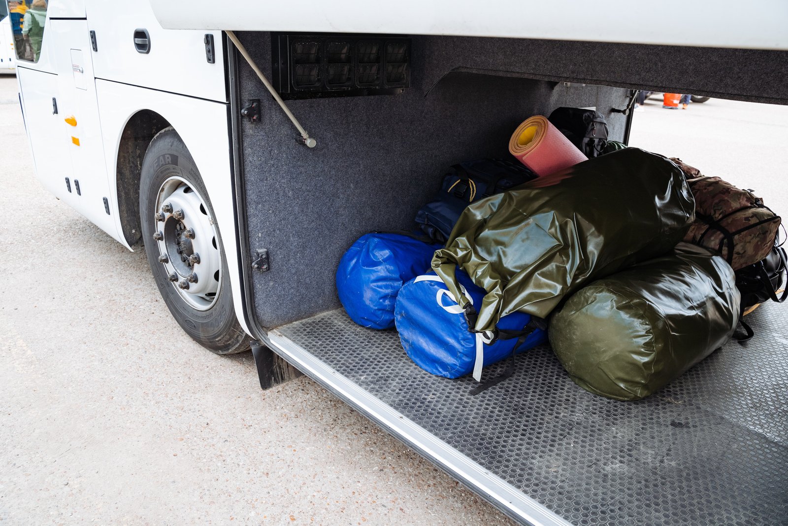 Luggage being loaded into the undercarriage storage bays of a charter coach bus